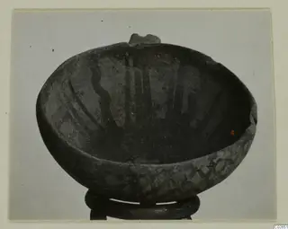 White Painted IV-V bowl with dark painted bands, shown on a ring stand against a grey background.