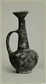 Pottery jug with a single loop handle, a flaring trefoil-like mouth and a rounded body, photographed against a plain background.