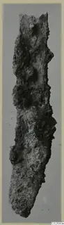 Heavily corroded iron knife blade, shown upright.