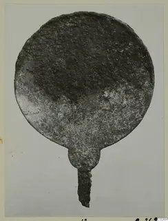 Corroded round metal disc with a narrow tang, photographed on a mounted card; from Marion Tomb 14