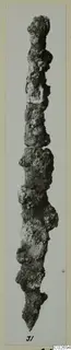 Corroded metal tool from Marion, long and narrow, tapering to a point at the lower end