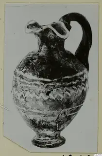 Black-glazed juglet with a trefoil mouth, a single strap handle and white painted bands and zigzag pattern on the body.
