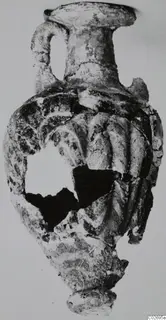 Glass amphoriskos with a ribbed body and single handle, from Marion Tomb 7; part of the body is broken away.