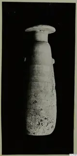 Tall pale stone vase with a wide flat rim and small side lugs, photographed against a black background