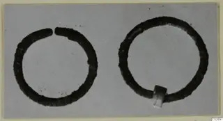 Two bronze earrings from Marion Tomb 85: one open ring and one closed ring with a small rectangular block.