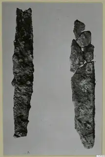 Two corroded iron knife blades from Marion, Tombs 6 A and 6 B, lying side by side on a plain grey background.