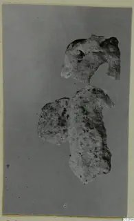 Two broken pieces of pale stone, probably from a vase, on a grey backdrop
