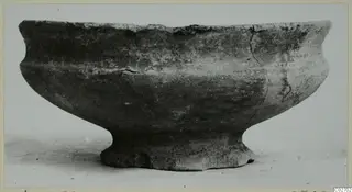 Pottery bowl with a flaring rim and a short foot, shown on a plain pale surface