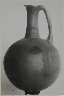 Jug of Red-on-Black etc pottery with a tall neck, single loop handle and bands of fine lines