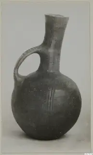 Round-bodied jug with a tall neck and a loop handle, dark surface with a few pale painted lines