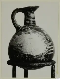 Pottery jug from Lapithos with a strap handle, grooved neck and globular body, on a metal stand