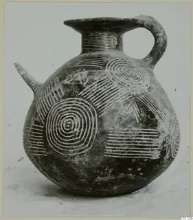 Dark polished jug with a side spout, a loop handle and incised concentric circles and bands on its body