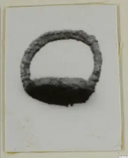Ring-shaped silver find with a round hoop open at the top, photographed on a white card mount.