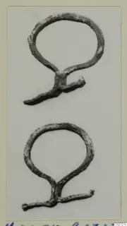 Two bronze loop-shaped fragments with short projecting arms, photographed on a pale background.