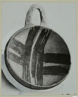 Pottery White Painted IV-V bowl with a loop handle and dark brushed bands, shown on a mounted photograph