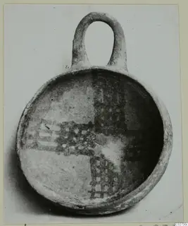 White Painted IV-V bowl with a loop handle, interior decorated with a cross-shaped grid pattern in dark paint