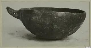 Red Polished IV bowl with a pierced flat handle, shown in side view on a pale surface