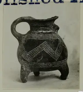 Red Polished III jug from Amathus with three feet, a looped handle and white lined chevron and band decoration