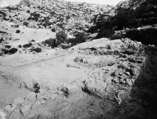 Excavated walls of the temple at Paradisiotissa, Vouni, seen from the north-west, with a rocky hillside behind.