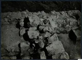Finds in situ at Cholades, Soli: a carved stone head lying among fallen blocks and rubble in an excavation.