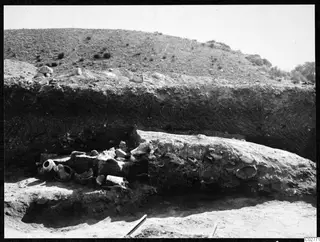 Excavated area at Mersinaki with a long rounded mass of soil and stone, and pottery vessels and sherds lying to its left
