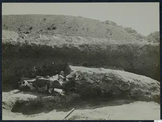 Excavated trench at Mersinaki with pottery vessels and sherds on the left beside a large stone block