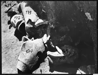 Broken stone fragments, probably parts of sculptures, lying in excavated soil at Mersinaki