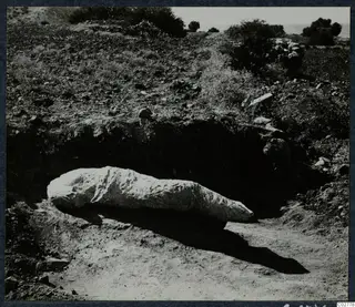 Large pale stone sculpture lying in situ in an excavated pit at Mersinaki