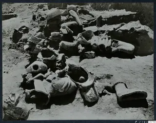 Statue fragments, including heads and a foot, lying together in an excavated area at Mersinaki