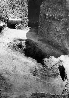 Pit H 14-15 at Mersinaki after excavation, with earth sections and a stone slab set into the wall