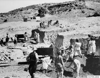 Men and women digging in an excavation at Mersinaki, with a cart on rails in the foreground