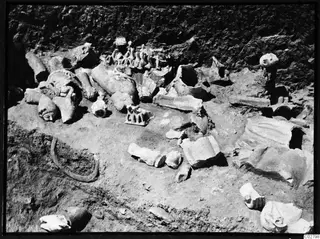 Sculpture fragments lying in an excavated trench at Mersinaki: several heads, limbs and small figurines among the debris