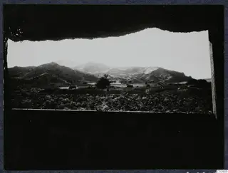 View through a tent opening over fields and hills toward Vouni at Mersinaki