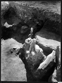Stone objects found in situ in Pit VI at Mersinaki, seen from above in an excavated pit with earth walls.