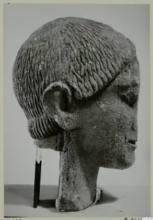 Limestone head from Kition, seen in profile, with incised hair rows and a large ear