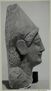 Limestone sculpture head from Kition, shown in profile facing right, with a tall headdress and carved hair.