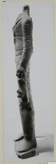Limestone statue of a standing figure seen in profile, head broken off at the top