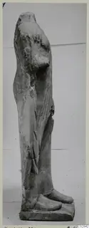 Side view of a headless limestone statue of a standing figure from Kition, on a rectangular base
