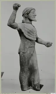 Limestone statue of a bearded standing male figure from Kition, one arm raised with a clenched fist