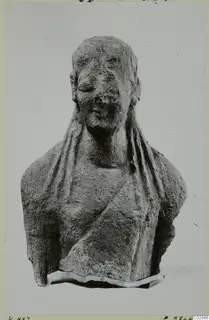 Limestone bust fragment from Kition, head and shoulders draped in a veil, face worn and nose damaged.