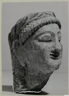 Limestone head from Kition, turned to the right, with a band across the forehead and hair falling behind the ears.
