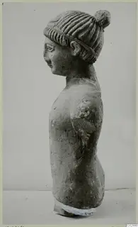 Limestone statue of a head and upper torso in profile, hair in a bun with a band, from Kition