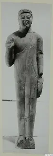 Standing limestone statue of a figure with a head band and one hand raised to the chest, from Kition