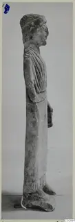 Limestone statue of a standing figure in profile, wearing a long draped garment