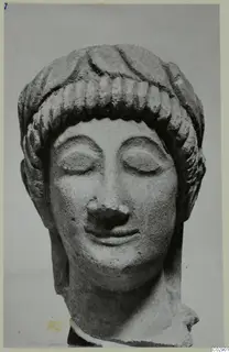 Limestone head of a statue with closed eyes and hair in rows of curls over the forehead