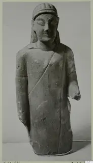 Limestone statue of a standing male figure from Kition, with a cloak across the chest and a broken right forearm