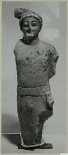 Limestone statue of a standing figure with a cap-like headdress, a belt and an arm broken off, from Kition.