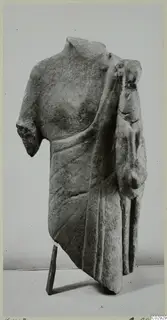 Limestone sculpture fragment of a draped torso with a smaller figure carved at its right side