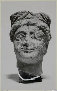 Limestone head fragment from Kition, front view against a plain grey background
