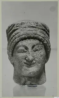 Limestone head from Kition with a ridged cylindrical headdress and a slight smile
